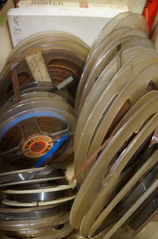 A box crammed with dusty reel-to-reel tapes of different sizes