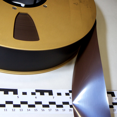 Section of large gold-coloured tape reel with shiny brown 2 inch tape with black back coating