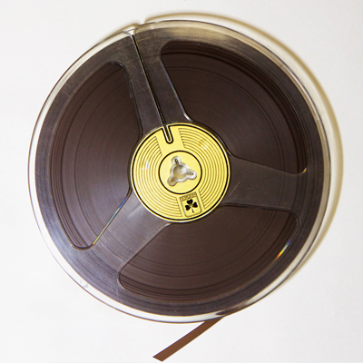 clear plastic 7 inch reel containing quarter inch brown magnetic audio tape