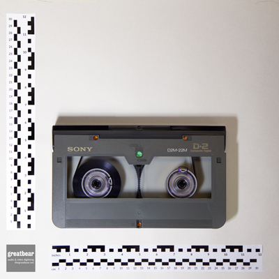 rectangular grey D-2 video cassette with rulers indicating width 25.4 cm by height 14.9cm.