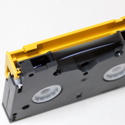 end view of cassette with yellow protective shield opened to reveal black shiny tape inside