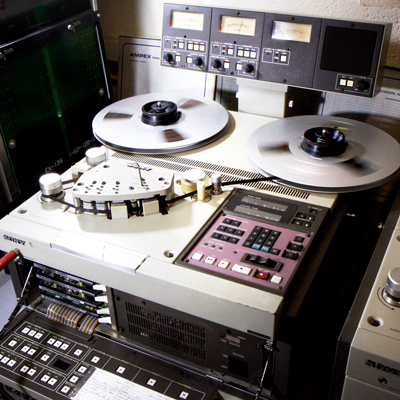 Reel-to-reel tape recorder with multiple gauges and switches and 2 large aluminium spools of tape spinning