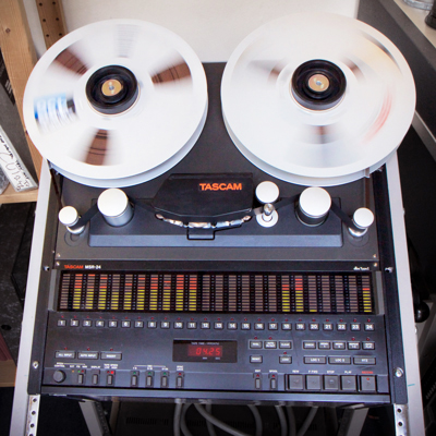 large tascam and ampex tape spools spinning on reel-to-reel tape machine with 24 track audio display